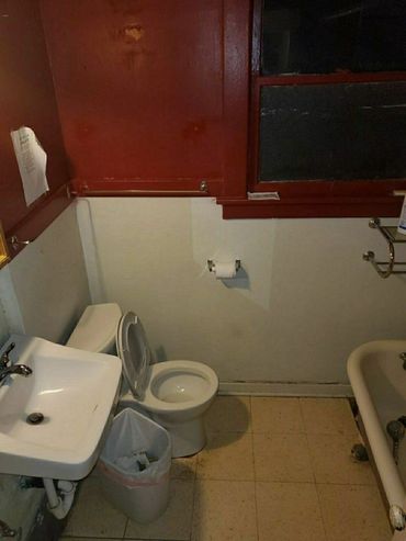 A small, dimly lit bathroom with a white sink, toilet, and bathtub.