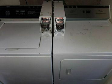 Two white commercial coin-operated Whirlpool laundry machines.
