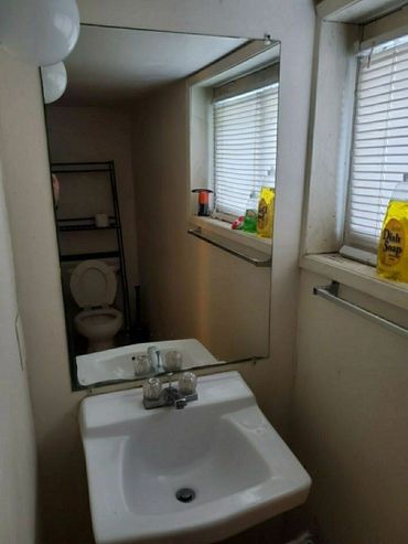 Small bathroom with a sink, mirror, and toilet in reflection.