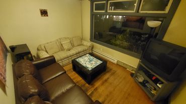 Cozy living room with two sofas, a patterned coffee table, and a TV near a large window.