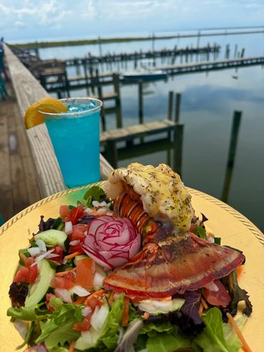 Grilled lobster tail salad with a blue cocktail by the waterfront.