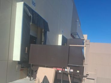 Loading dock area with dumpsters and cardboard waste under a clear blue sky.
