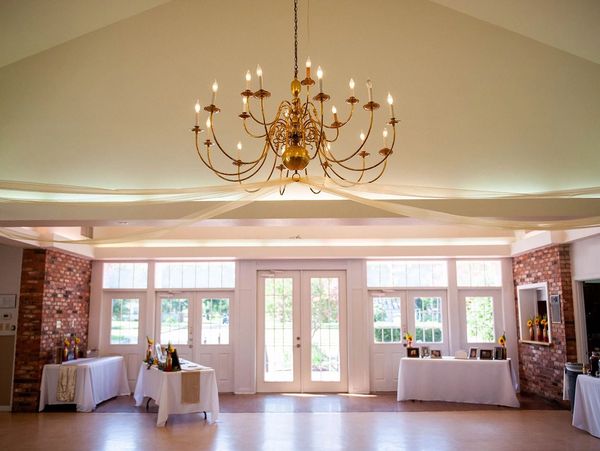 Elegant event space with chandelier and tables by large windows.
