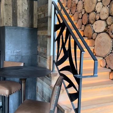 Cozy seating area next to a warmly lit wooden staircase with a log wall.