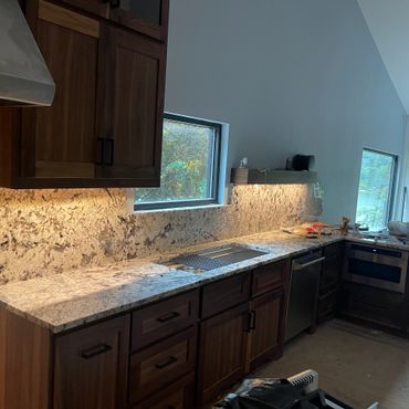 Modern kitchen with granite countertops and wooden cabinets under natural light.