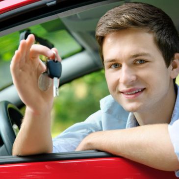 Young man holding car keys while sitting in a red car.