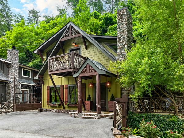 Rustic green cabin with wooden accents nestled in lush greenery.
