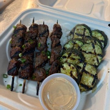 Grilled beef skewers with zucchini and dipping sauce.