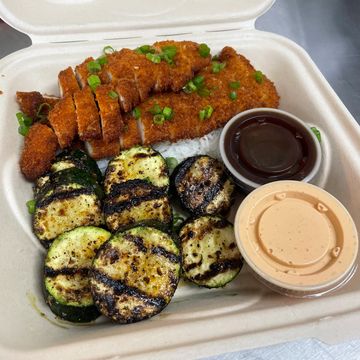 Grilled zucchini, breaded chicken with sauces in a takeout container.