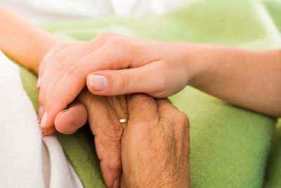 Younger hand holding older hand gently.
