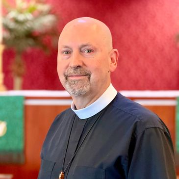 Clergyman in black robe with clerical collar in a church.