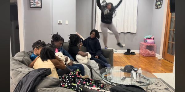 A group sitting on a couch with one person jumping in the background.