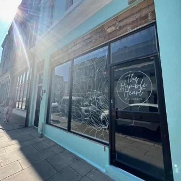 A serene landscape featuring a calm lake surrounded by mountains and lush greenery under a clear blue sky.