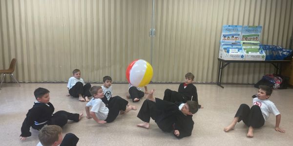 Kids playing with a colorful beach ball indoors.