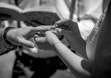 A bride slips a ring on her groom's finger.