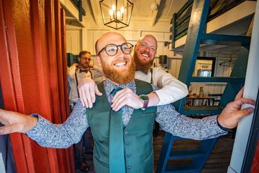 A best man helps a groom tie his tie.