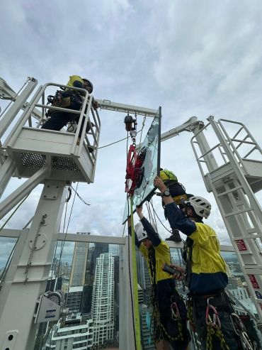 Workers installing glass on a high-rise building.
