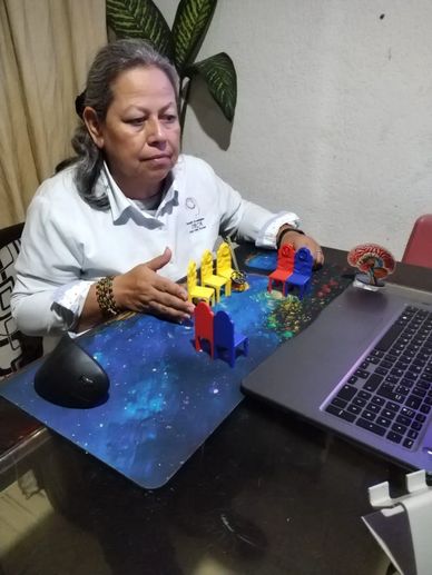 Woman interacting with colorful miniature chairs in front of a laptop.