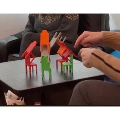 Colorful miniature chairs stacked creatively on a table.