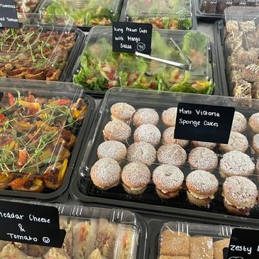 Assorted food trays with mini Victoria sponge cakes.