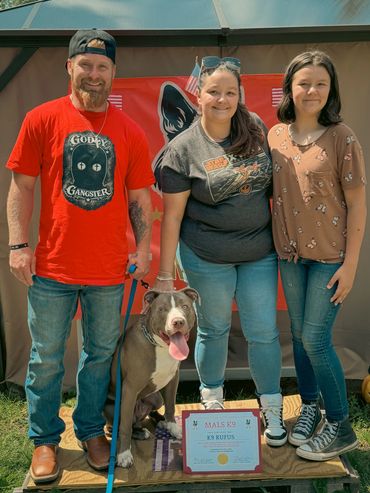 Three people with a dog and a K9 training certificate.