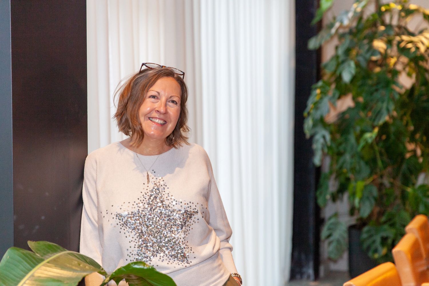 Smiling woman wearing a sequin star sweater indoors.
