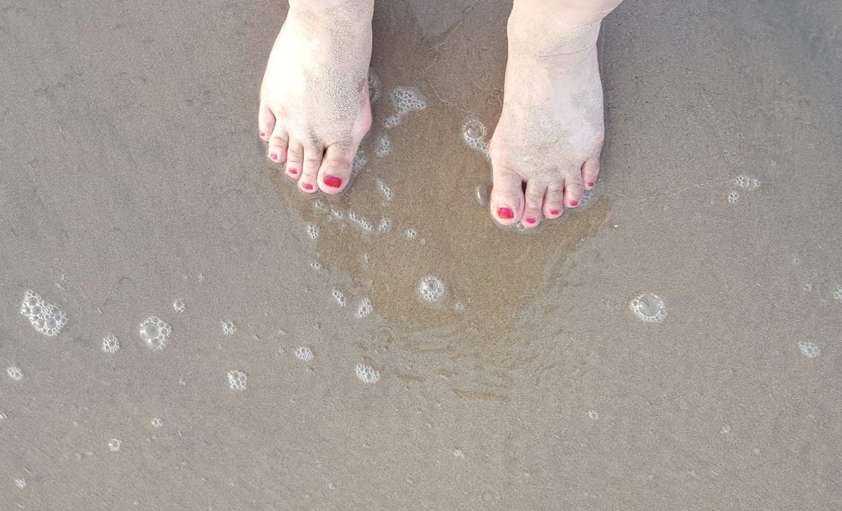 My feet on the sand near the ocean.