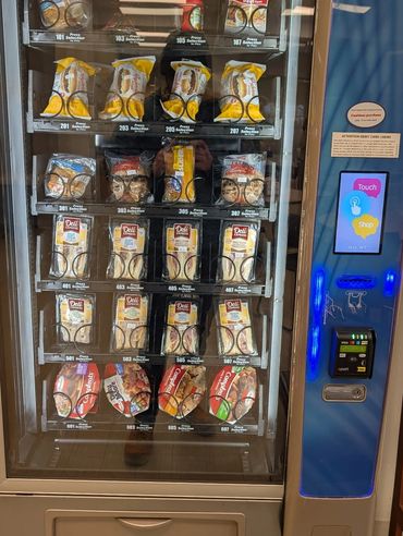 Vending machine stocked with sandwiches, snacks, and instant lunch options.