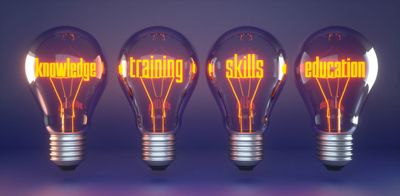 Four glowing light bulbs with words knowledge, training, skills, and education inside.
