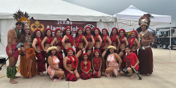 Group of people in traditional Polynesian attire posing outdoors.