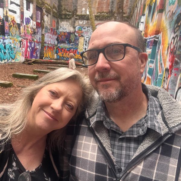 Couple smiling in colorful graffiti-covered courtyard.