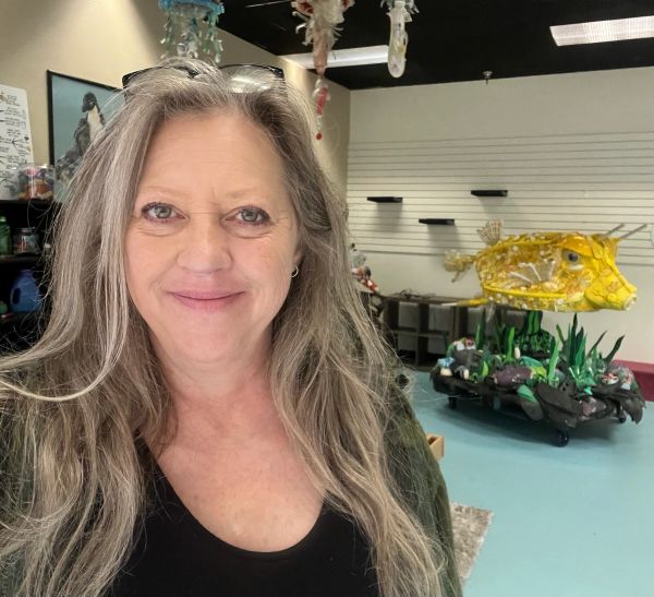 Smiling woman with long gray hair indoors.