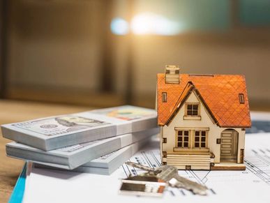 Miniature house with keys and money on documents.