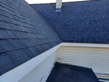 Blue shingled roof with white siding and chimney detail.