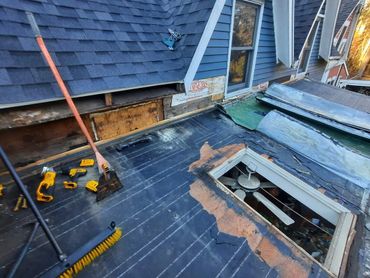 Roof repair in progress with tools and damaged areas visible.