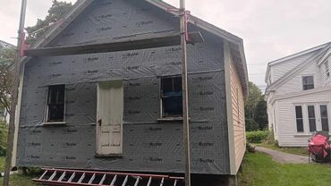 House under renovation with protective wrap and no front steps.