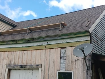 Roof scaffolding on a rustic building with a satellite dish attached.