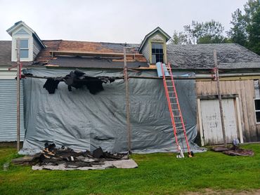 House undergoing roof repairs with scaffolding and a ladder in place.