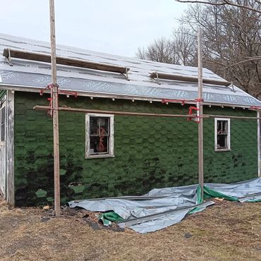 A green hexagonal-patterned building under roof construction with scaffolding.