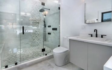 Remodeled bathroom with new vanity, tiled shower walls and floor with newly installed glass panels