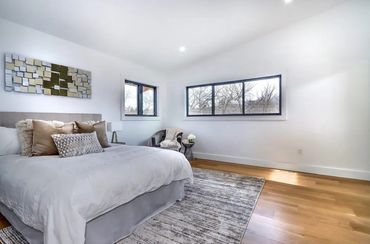 Remodeled bedroom with newly installed hardwood flooring, recessed lighting, & triple pane windows