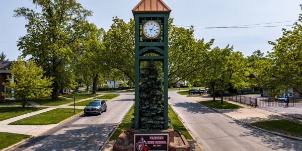 Street clock tower in a green neighborhood.