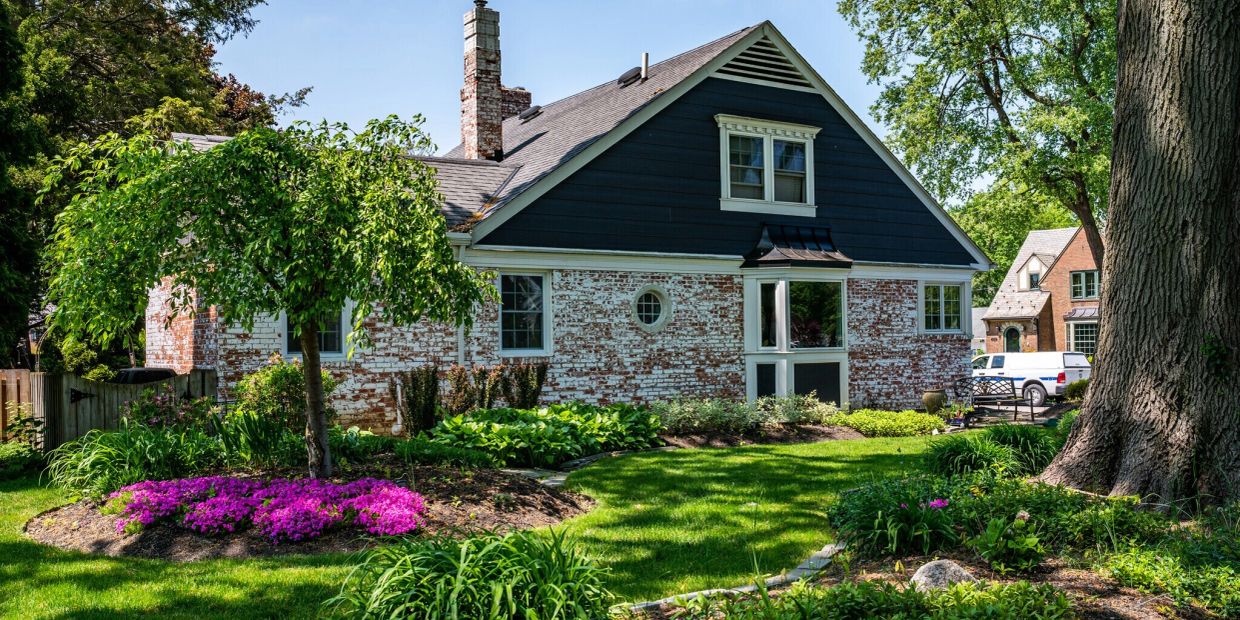 Cozy house with a colorful garden and trees.