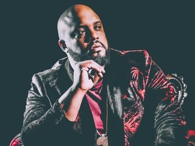 Man in velvet jacket posing thoughtfully.