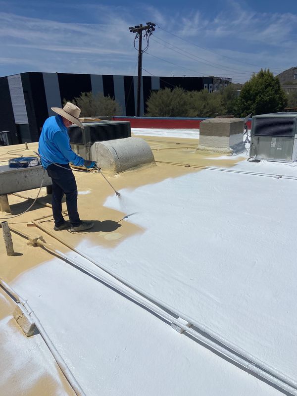 A man working on roof  to apply a polyurea elastomeric coating