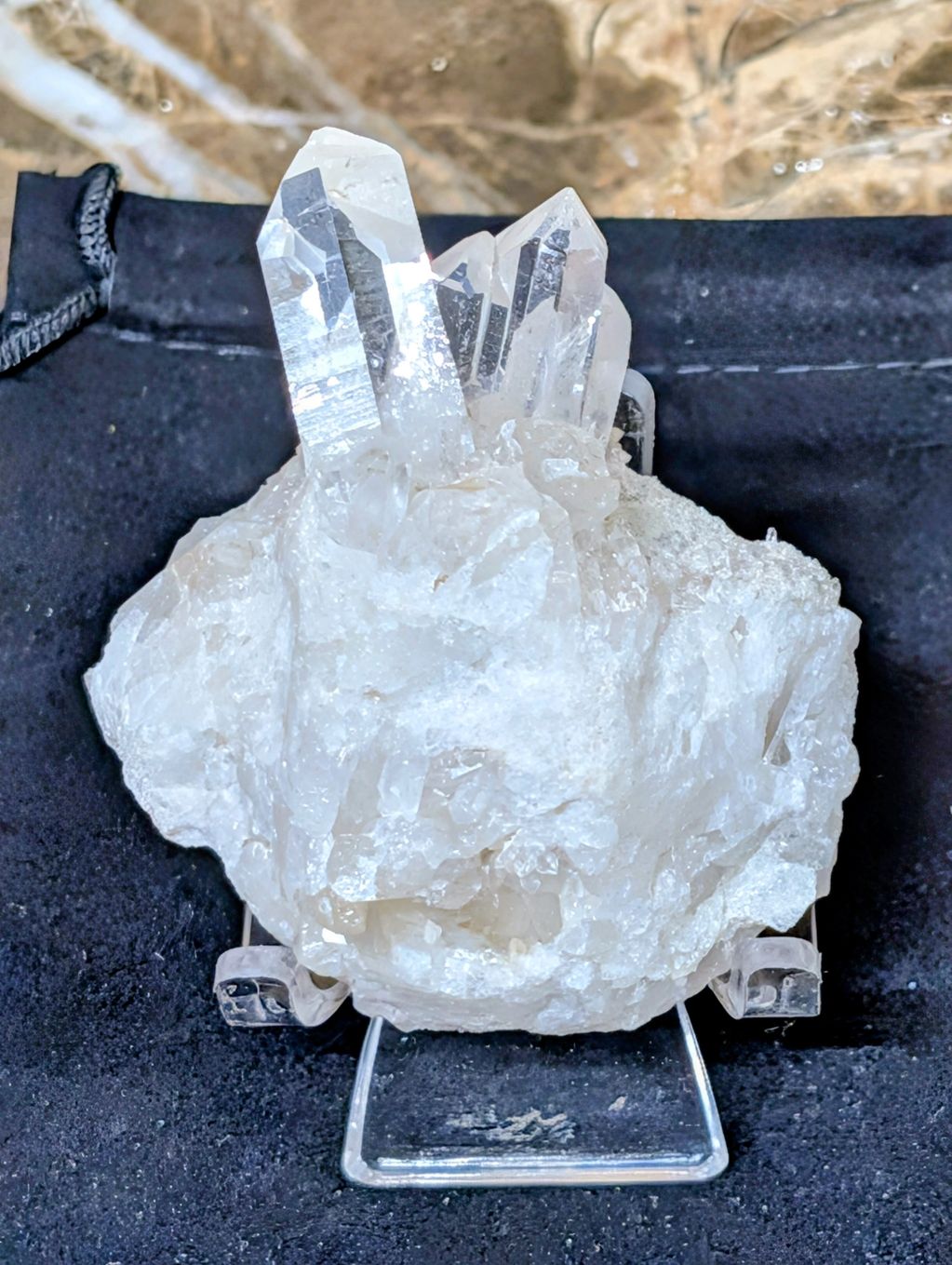 Clear quartz crystal cluster on display stand.