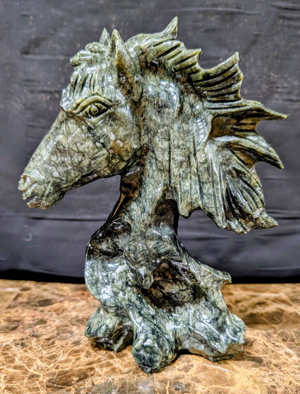 Green marble horse head sculpture with intricate details.