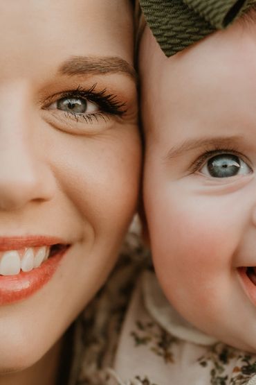 Close-up of a smiling woman and baby with bright blue eyes.