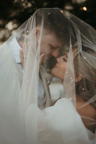 A tender moment between bride and groom under a veil.