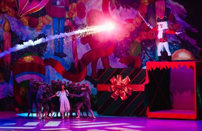 A Nutcracker-themed stage performance with dancers and a large gift box.
